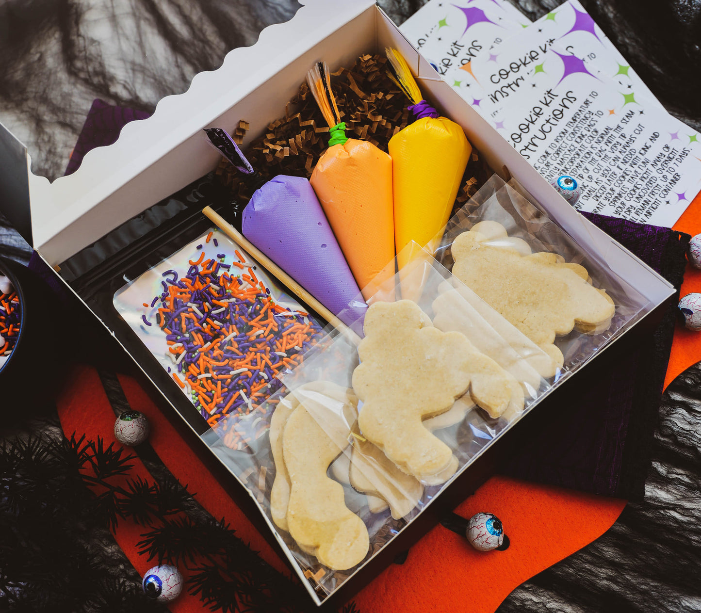 Halloween-themed cookie decorating kit with cookies, icing, and sprinkles in a box.