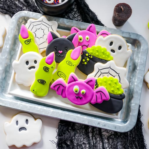 Decorative Halloween cookies on a tray with ghost, bat, and spider designs.